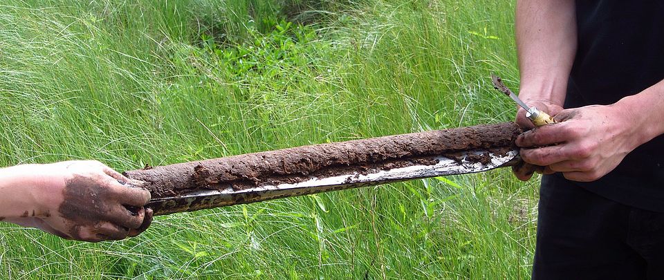 Zwei Hände halten einen Bohrkern mit Bodenprobe